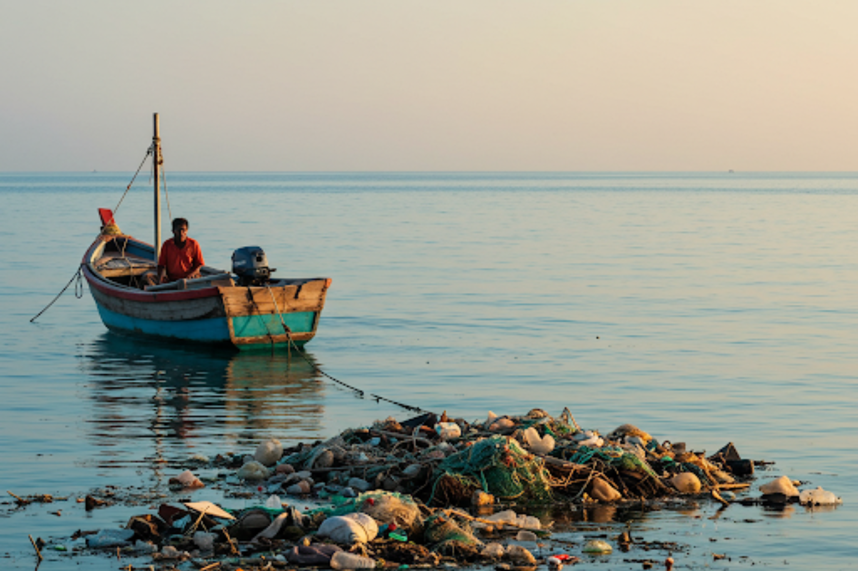 The threat of plastic pollution to Malaysia's coastlines, as seen with this fishing boat and floating debris. Greencleani is committed to reducing plastic waste for healthier oceans