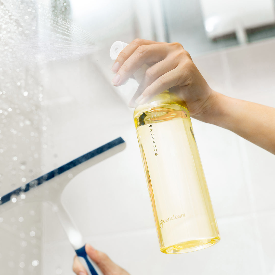 A Malaysian mum safely cleaning her bathroom shower with Greencleani's non-toxic, plant-based bathroom cleaner from the Eco-Starter Kit